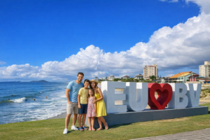 Família posando para foto no letreiro Eu amo Barra Velha