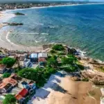 Imagem aérea de praia de Itapoá, com vista do mar, area e bairro.